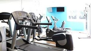 A gym with treadmills, exercise bikes, and a blue wall.