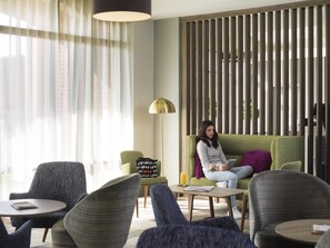 Un área de descanso moderna con sofá, sillones y una mesa de centro.