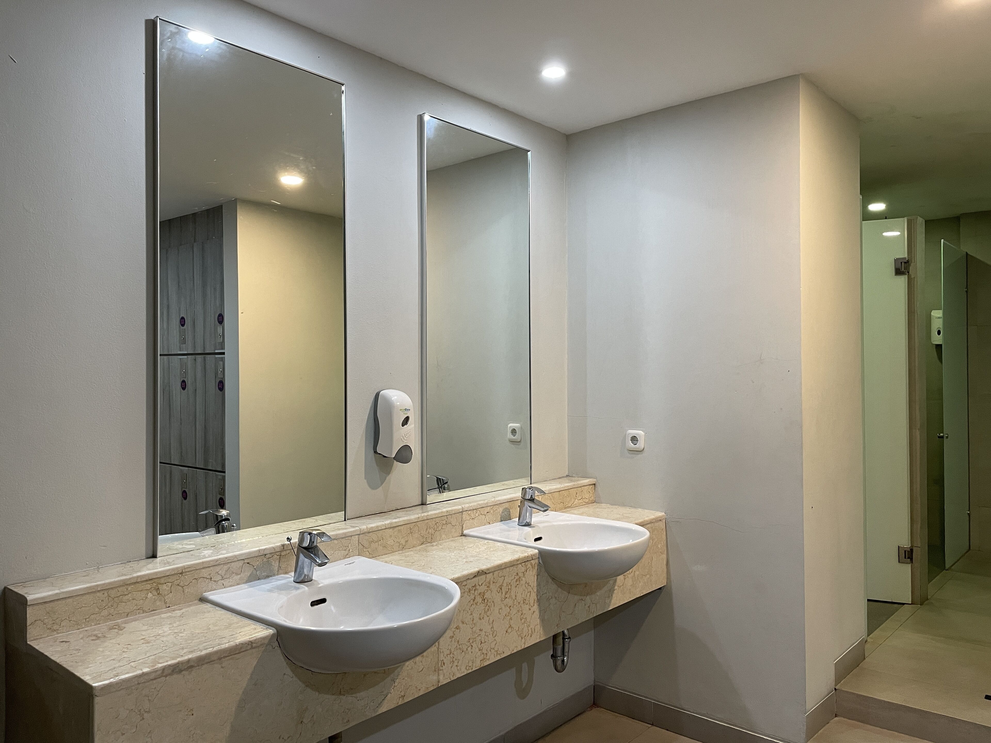 Un baño con dos lavabos, un espejo grande y un secador de manos.