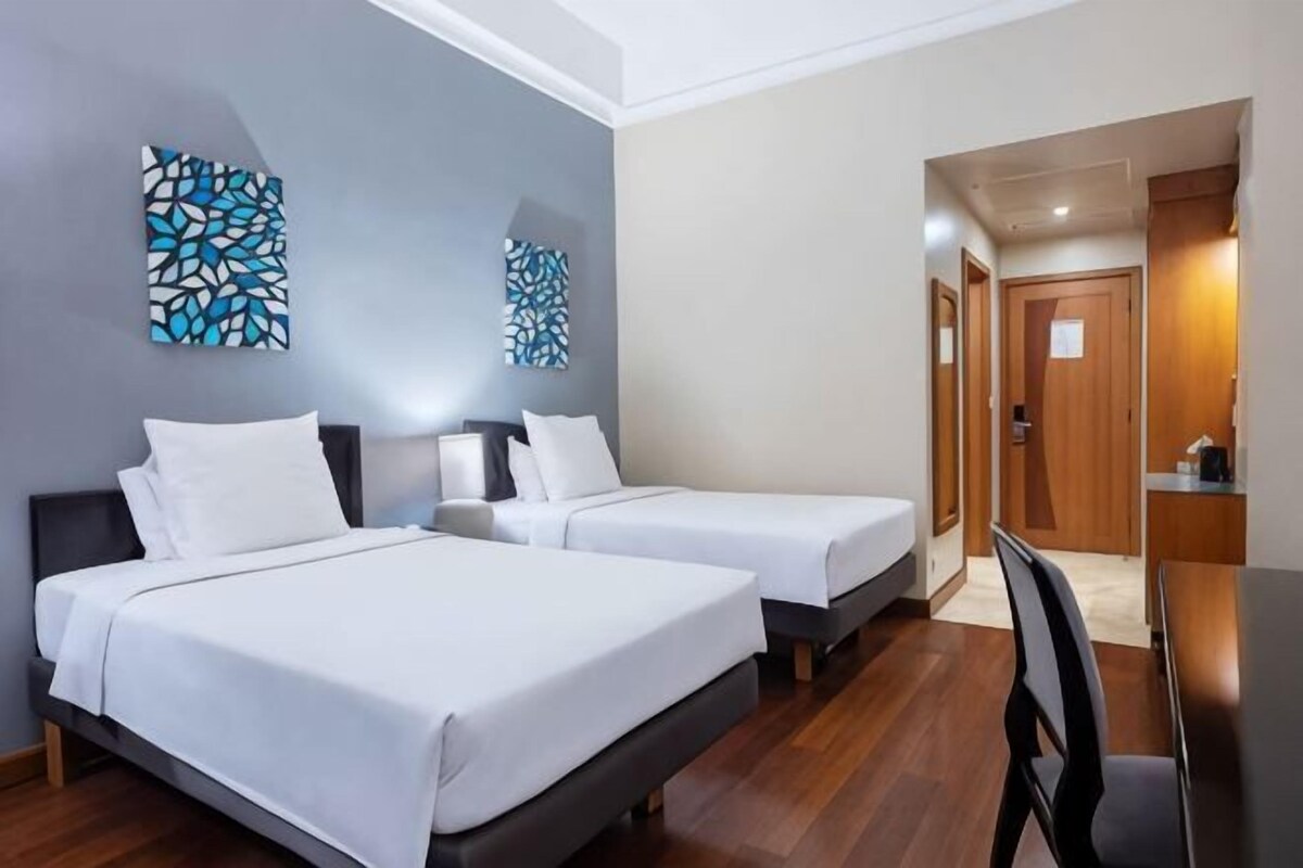 Une chambre d’hôtel avec deux lits, un bureau et une chaise.