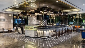 Un área de bar moderna con techo curvo, taburetes y una barra central.