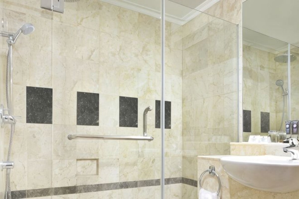 Un baño con cabina de ducha de vidrio, un lavabo y un espejo.