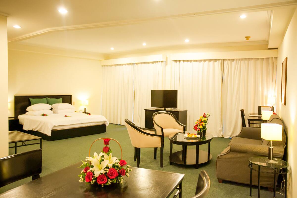 Une chambre d’hôtel comprenant un lit, une télévision, un bureau avec une lampe, une chaise et un canapé.