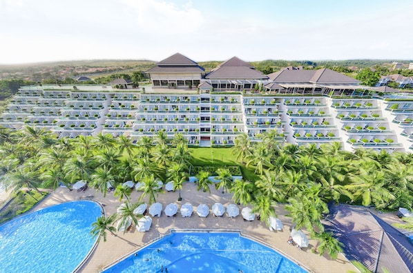 Un resort con varios edificios de hotel, una gran piscina y palmeras.