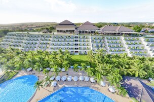 A resort with multiple hotel buildings, a large swimming pool, and palm trees.