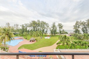 A resort with a swimming pool, a beach area, and palm trees.