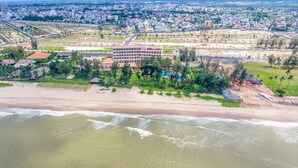 An aerial view of a coastal area with a large hotel complex, beachfront, and surrounding residential buildings.