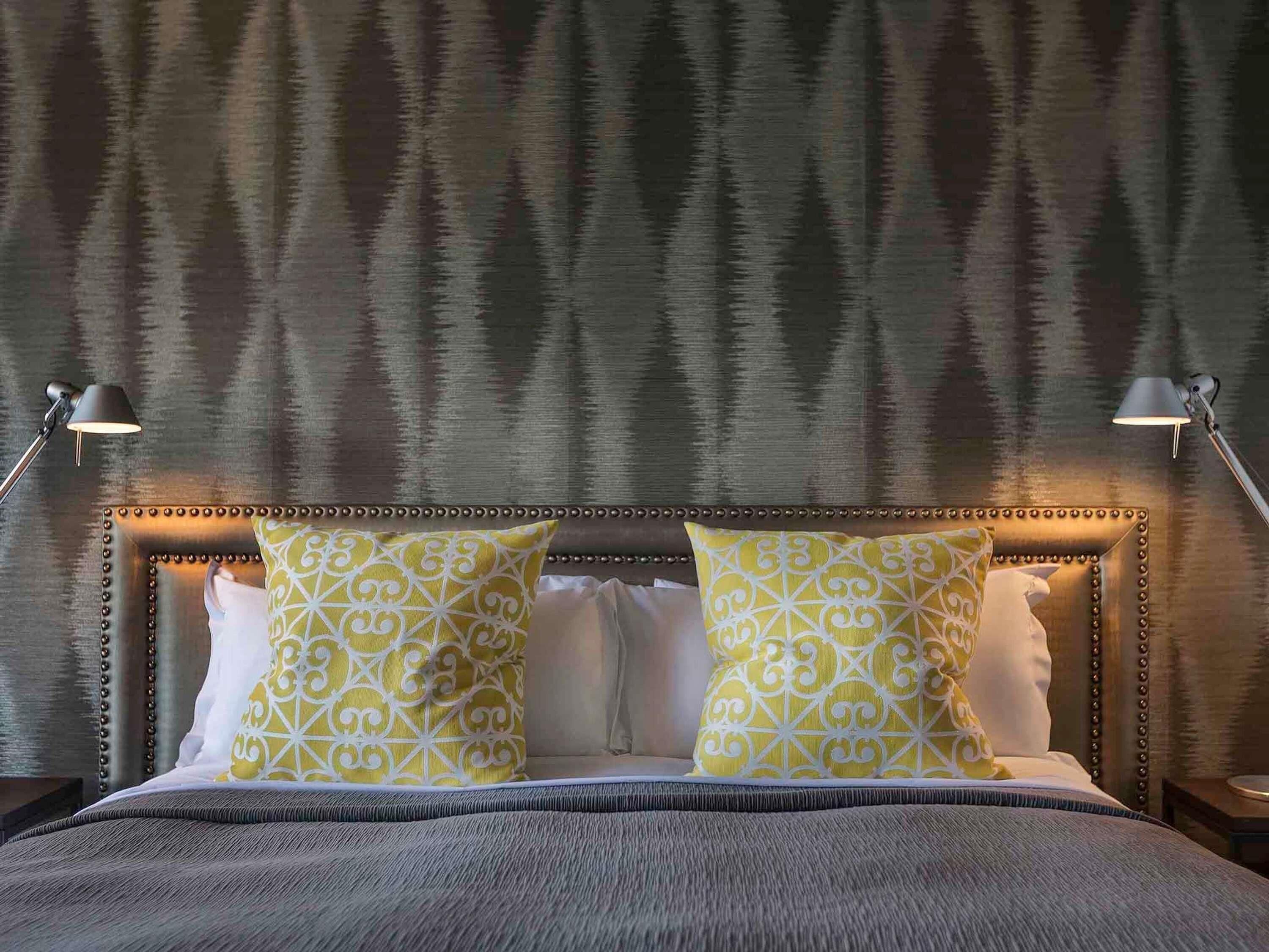 A bed with a tufted headboard, two bedside lamps, and patterned pillows.