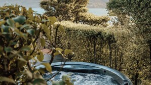 A hot tub on a wooden deck with a mountainous backdrop and a body of water. - Hotel St Moritz, Queenstown - MGallery (Queenstown)