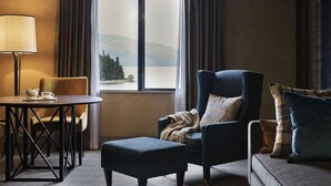 A hotel room with a view of a lake and mountains, a round table with a lamp, a sofa, and a chair. - Hotel St Moritz, Queenstown - MGallery (Queenstown)