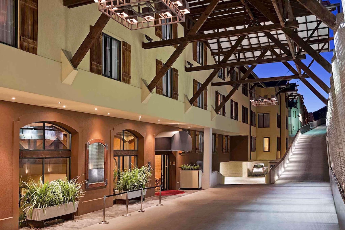 A hotel with a covered outdoor area, a staircase, and a red carpet.