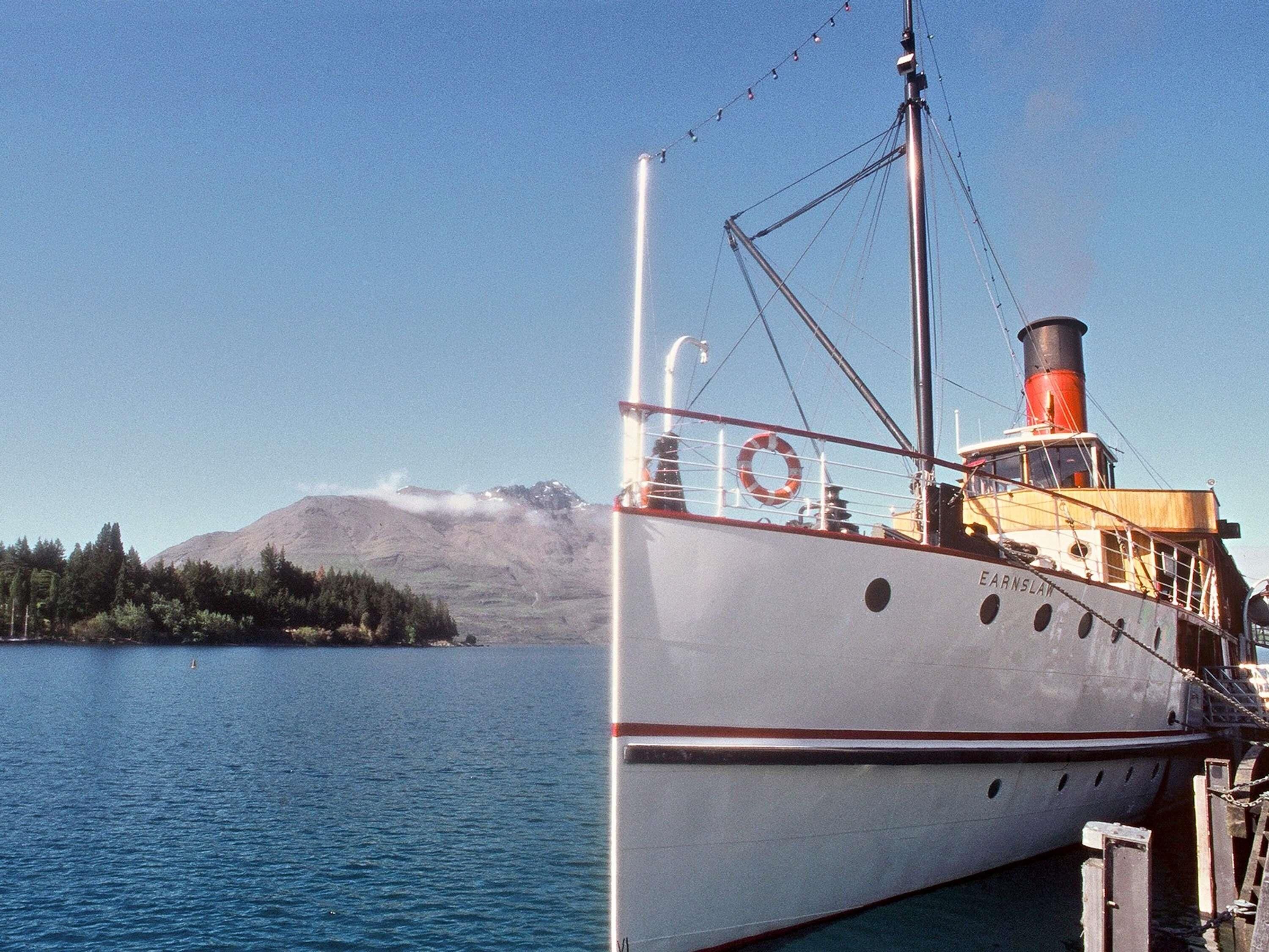 A boat docked at a pier with a mountainous backdrop.