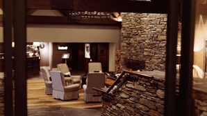 A stone wall with a fireplace, a staircase, and a seating area with chairs. - Hotel St Moritz, Queenstown - MGallery (Queenstown)
