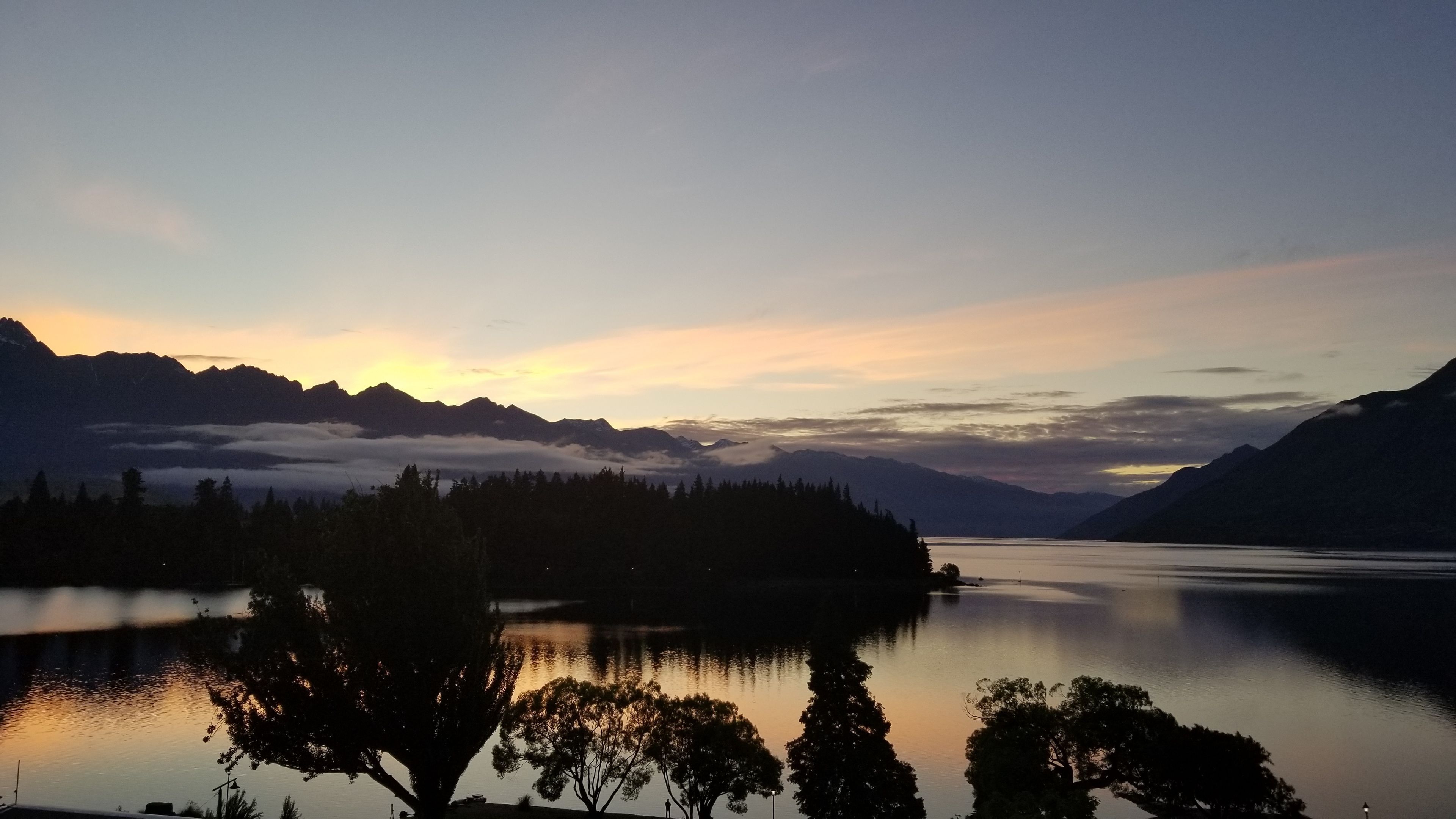 A calm lake at sunset with mountains in the background.