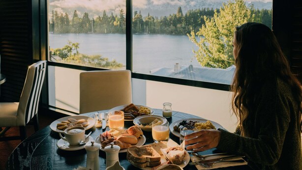 A dining table with breakfast items and a view of a lake and mountains. - Hotel St Moritz, Queenstown - MGallery (Queenstown)