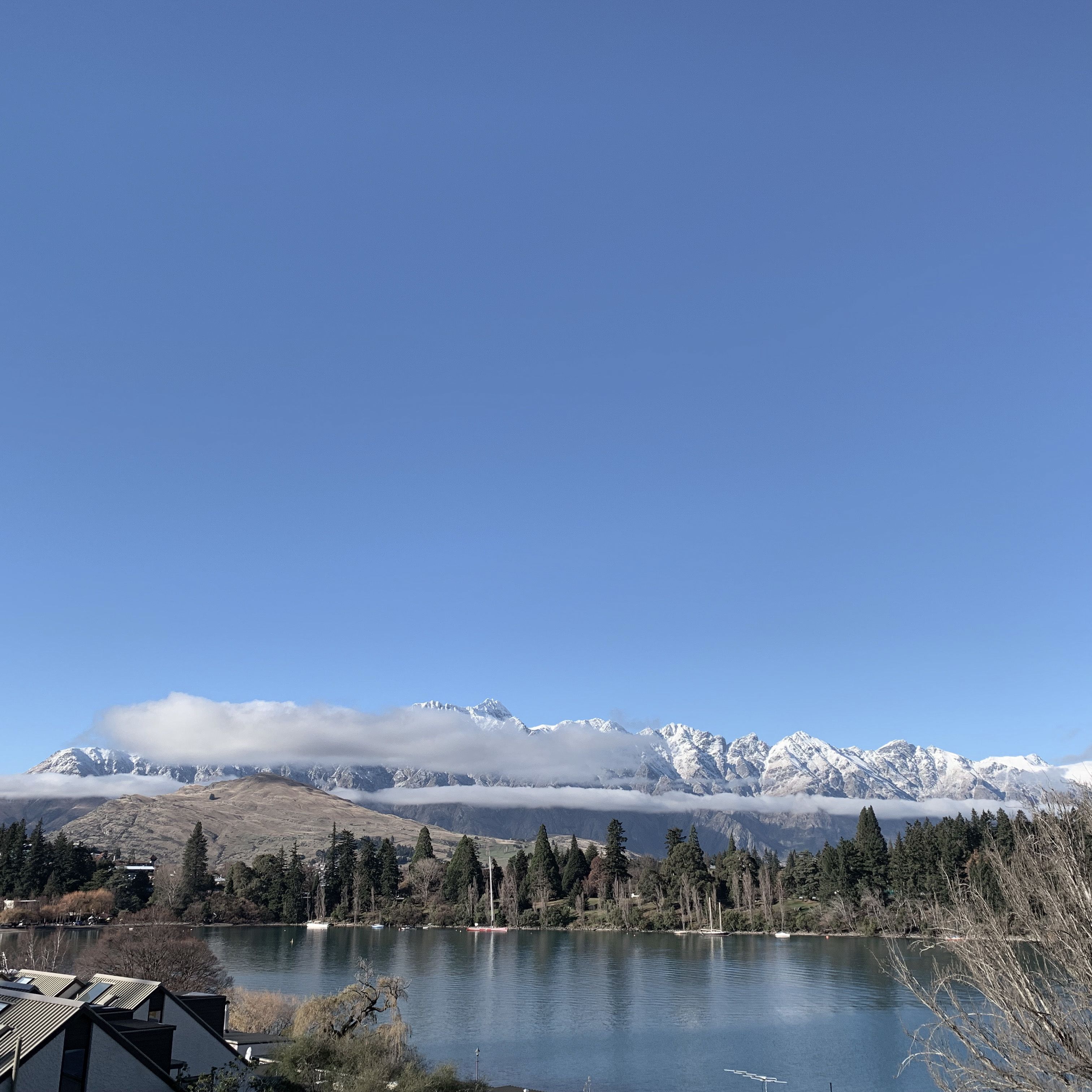 A lake with mountains in the background and a few buildings in the foreground.
