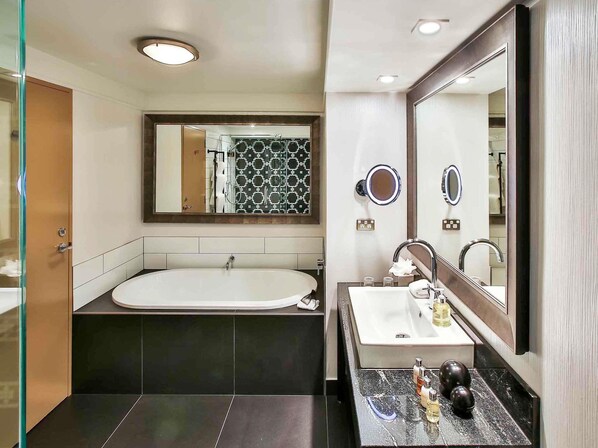 A modern bathroom with a bathtub, a vanity with a mirror, and a shower area.