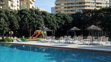 Una piscina techada, una piscina al aire libre, sombrillas