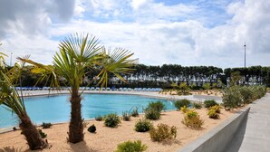 A pool area with palm trees, lounge chairs, and a clear sky. - Axis Vermar Conference & Beach Hotel (Povoa De Varzim)