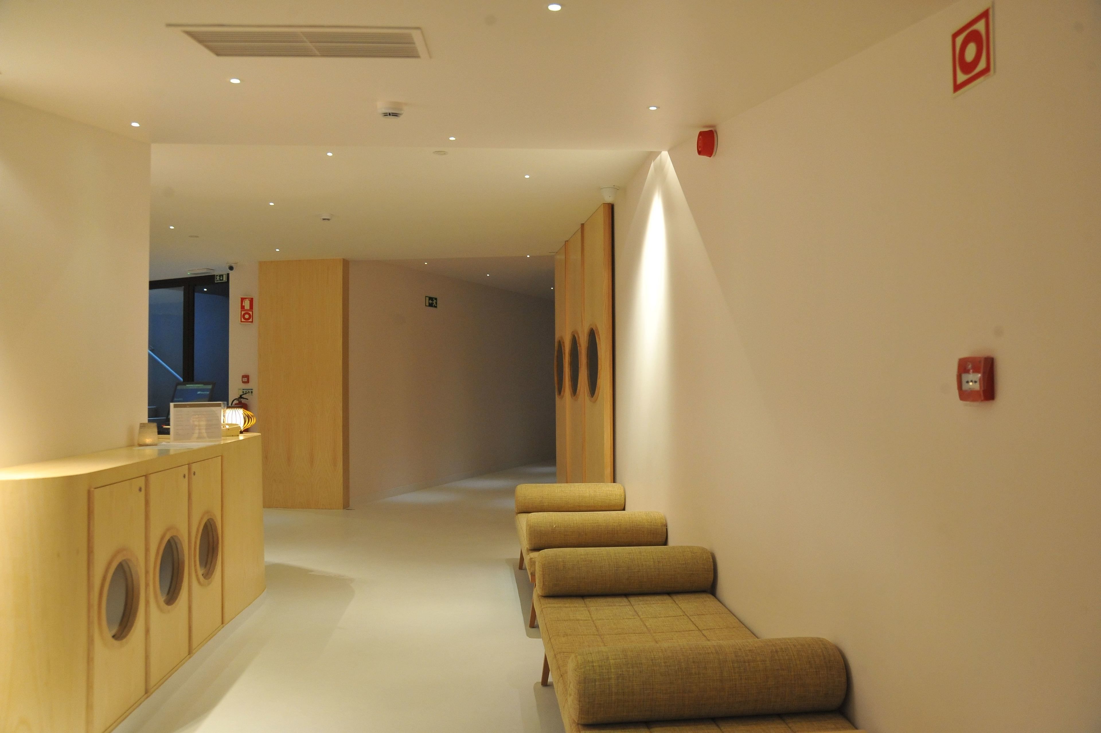 A hallway with a reception desk, a wooden cabinet with circular handles, and a bench with a checkered pattern.