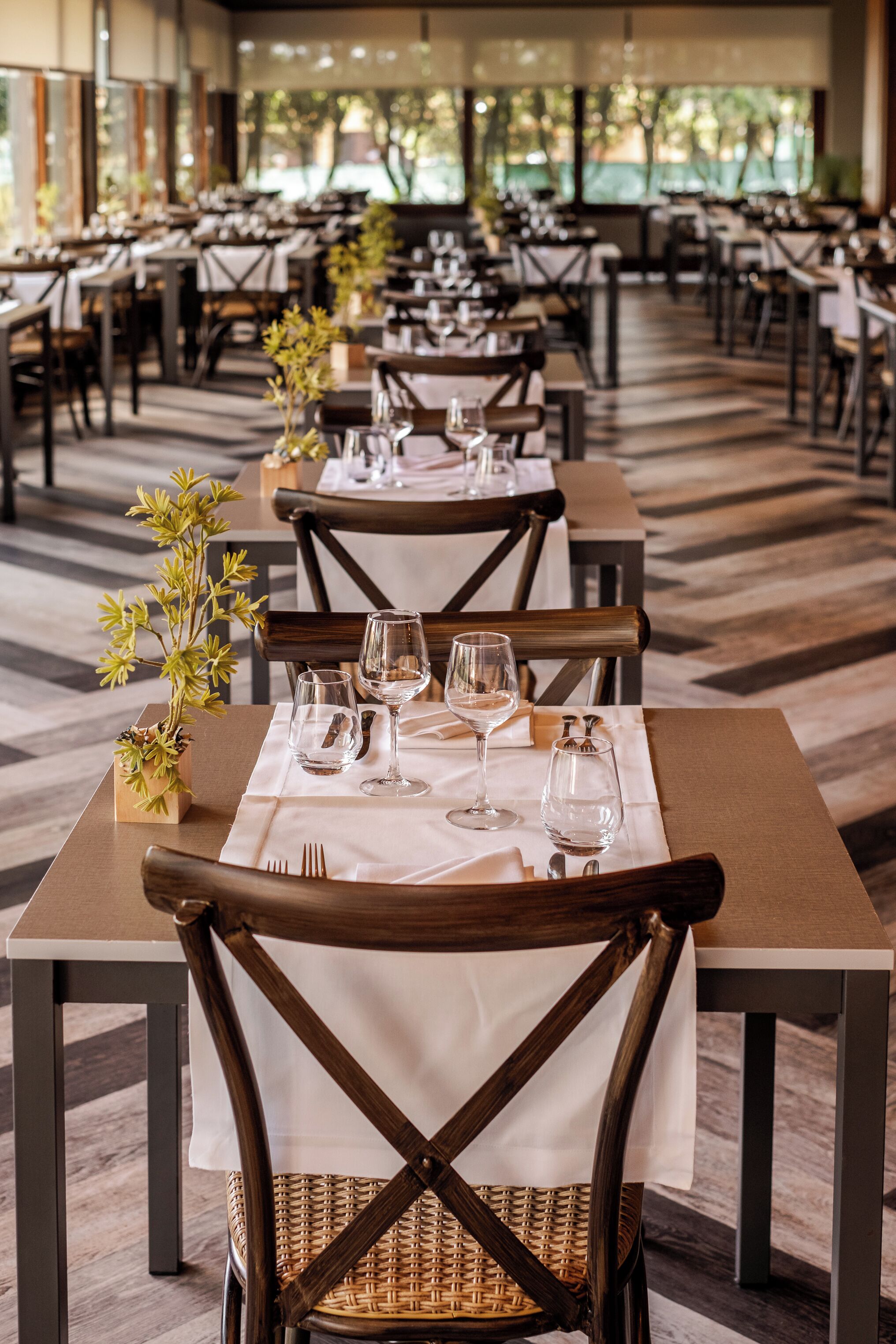 Un ristorante con diversi tavoli apparecchiati, sedie in legno e un pavimento decorato.