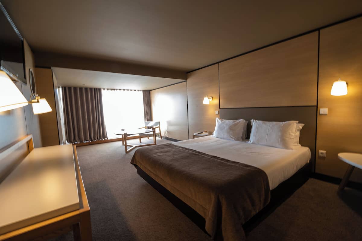 A hotel room with a large bed, bedside tables, a desk, and a chair.