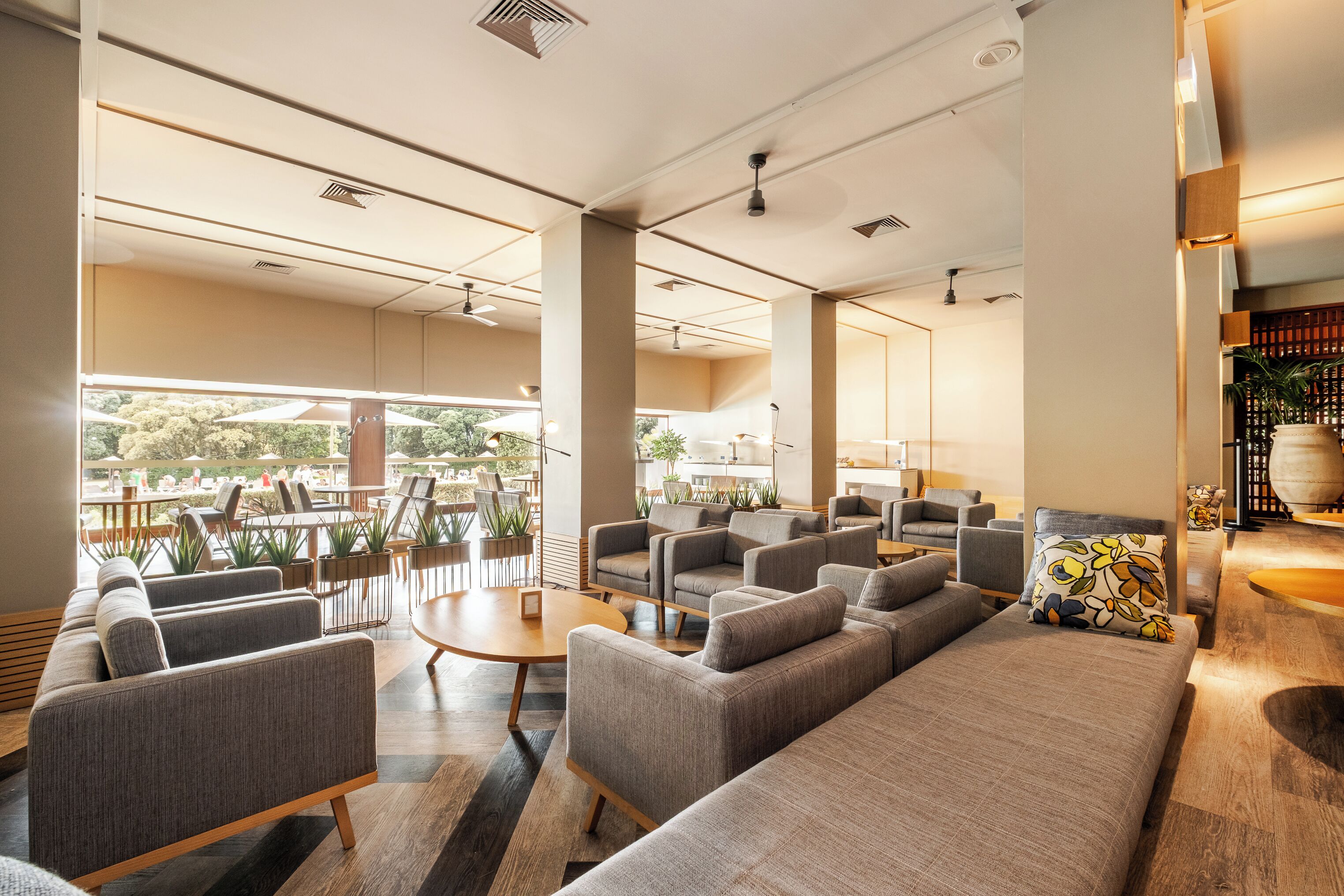 Un área de descanso moderna con sofás, sillones y una mesa de centro, con ventanas amplias y vistas al exterior.