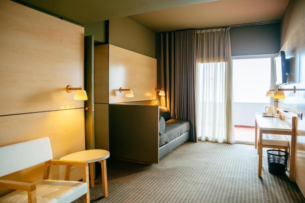 Een hotelkamer met een bed, een bureau, een stoel en een klein tafeltje.