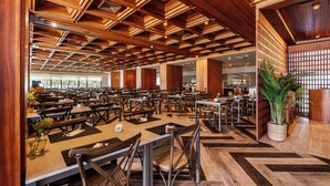 A spacious restaurant with wooden ceiling beams, multiple tables and chairs, and a large potted plant. - Axis Vermar Conference & Beach Hotel (Povoa De Varzim)