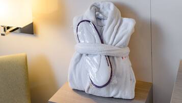 A white bathrobe on a wooden nightstand with a lamp in the background.