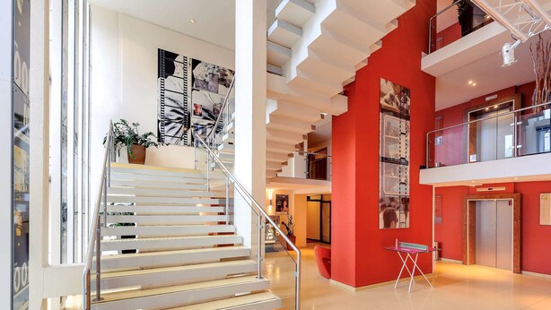 A modern interior with a staircase, red walls, and a mezzanine level. - Mercure Hotel Stuttgart Sindelfingen an der Messe (Sindelfingen)