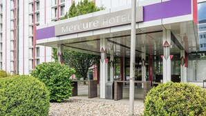 A modern hotel entrance with a covered walkway, a sign reading "Mercure Hotel," and a flagpole with a flag. - Mercure Hotel Stuttgart Sindelfingen an der Messe (Sindelfingen)