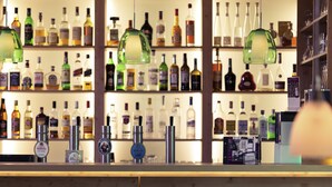 A bar area with multiple liquor bottles, a cash register, and stools. - Mercure Hotel Stuttgart Sindelfingen an der Messe (Sindelfingen)