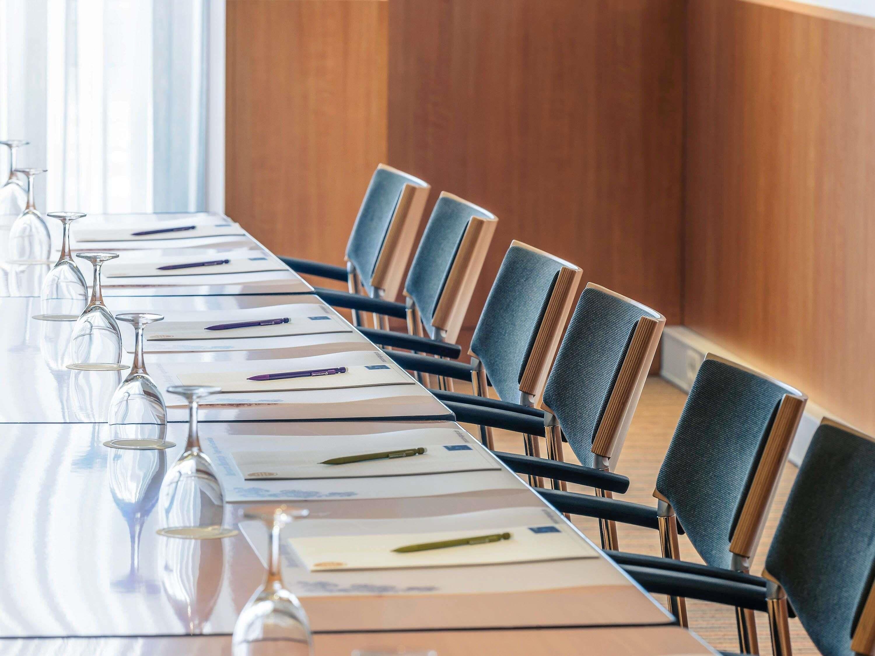A conference room with a long table, chairs, and wine glasses.