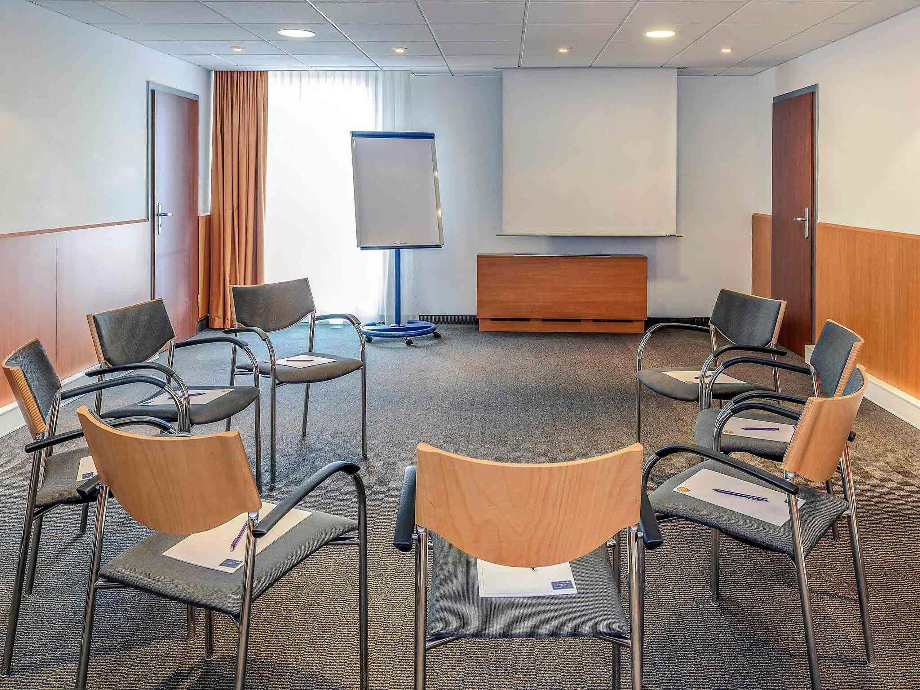 A conference room with a whiteboard, a projection screen, and a wooden cabinet.