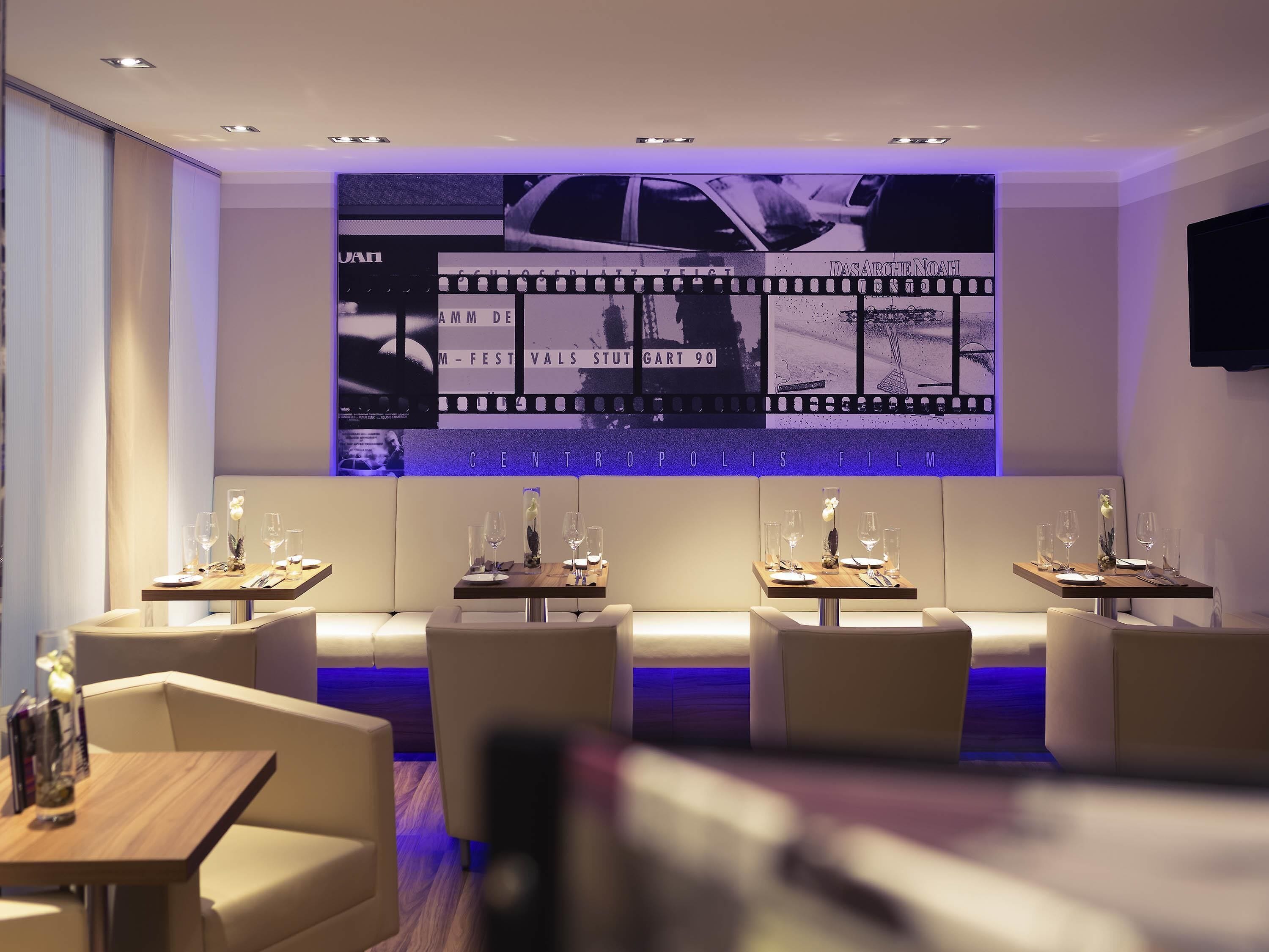 A modern restaurant with a film-themed wall, multiple dining tables, and comfortable seating.