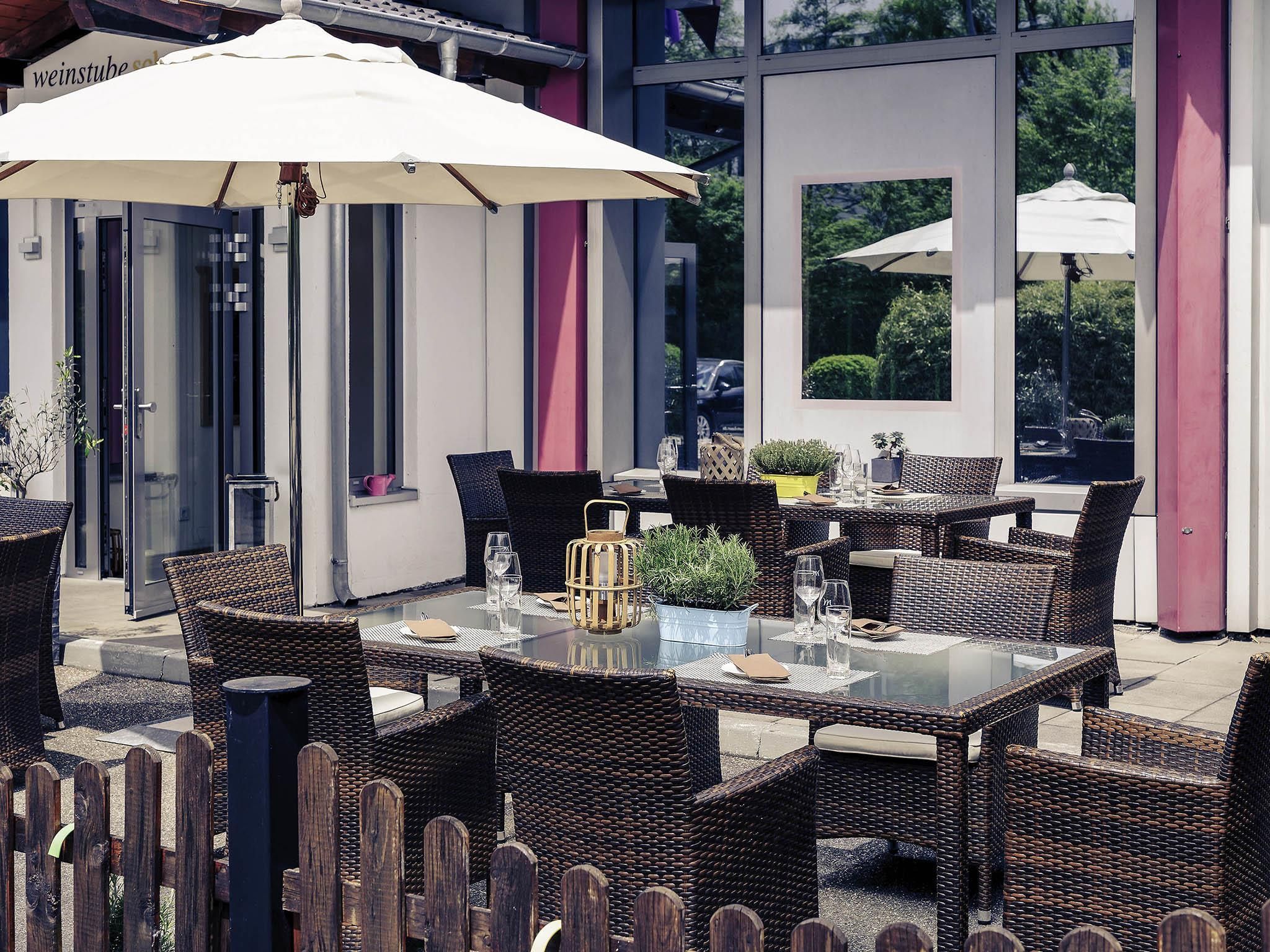 Un patio al aire libre con muebles de mimbre, mesas de vidrio y sombrillas.
