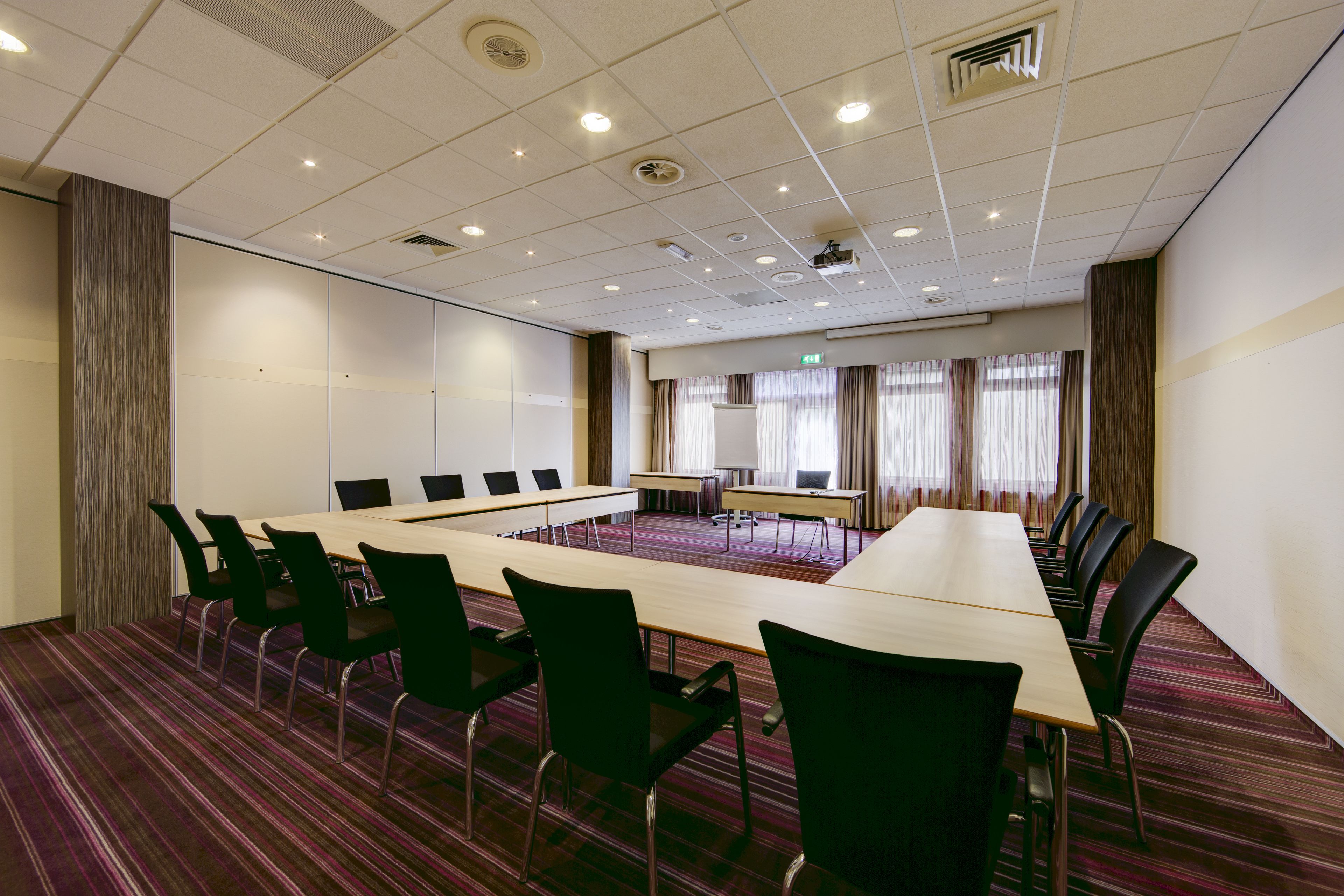 A conference room with a long table, multiple chairs, and a projector screen.