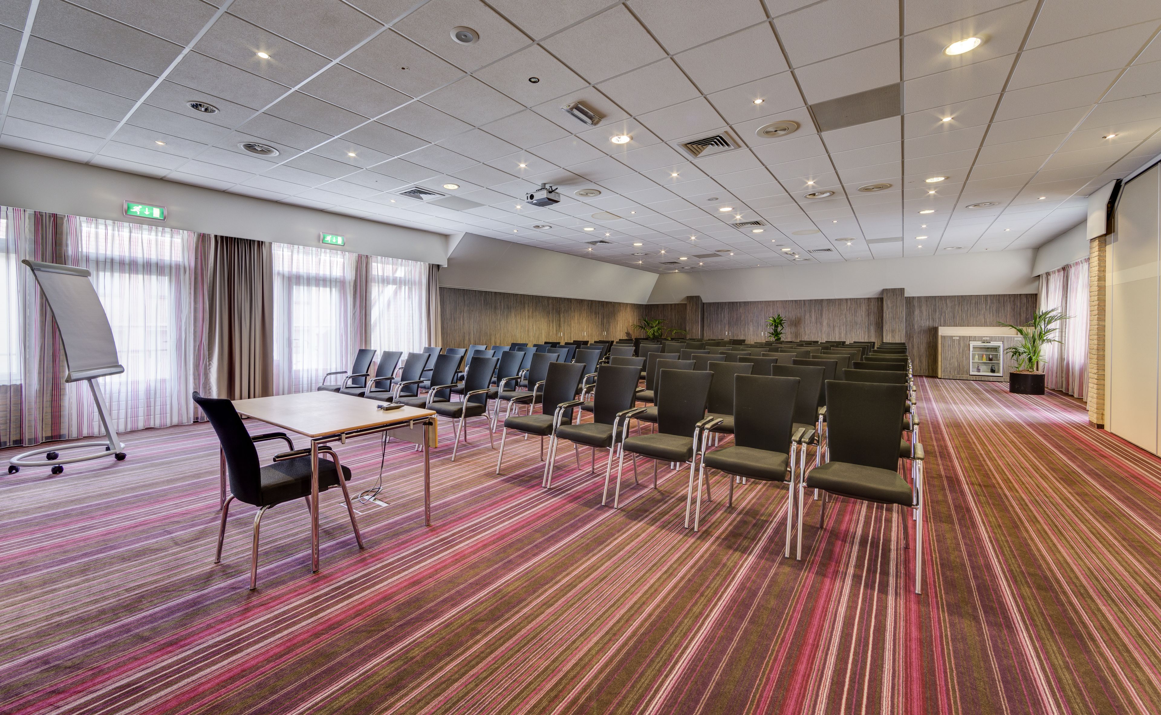 A conference room with rows of chairs, a projector, and a whiteboard.