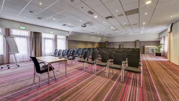 A conference room with rows of chairs, a projector, and a whiteboard.