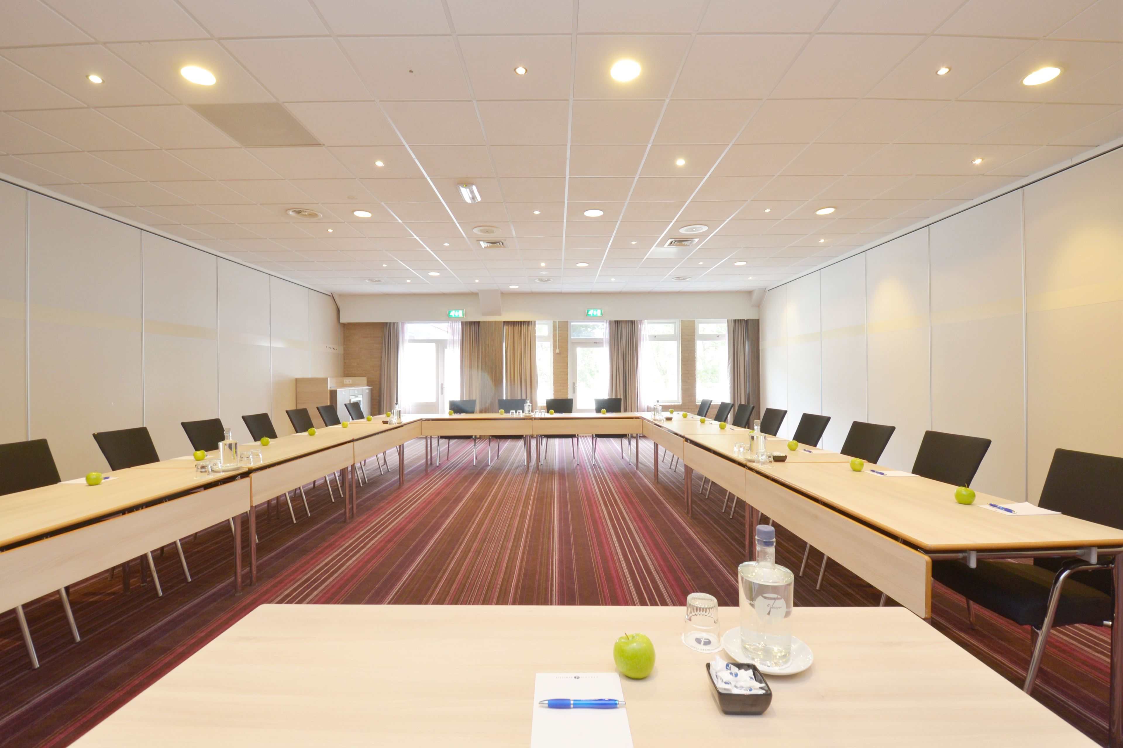 A conference room with a long table, chairs, and a striped carpet.