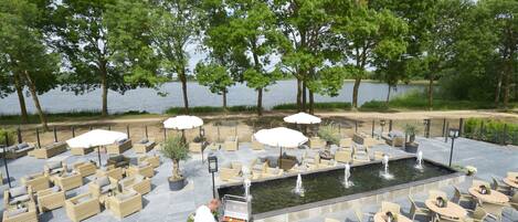 An outdoor patio with wicker furniture, a grill, and a water feature.