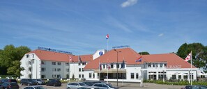 A hotel with a red roof, multiple flags, and a bar/restaurant. - Fletcher Hotel - Restaurant's - Hertogenbosch (Rosmalen)