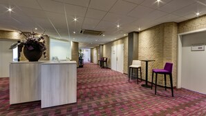 Un hall de hotel con mostrador de recepción, zona de estar y pared de ladrillo.