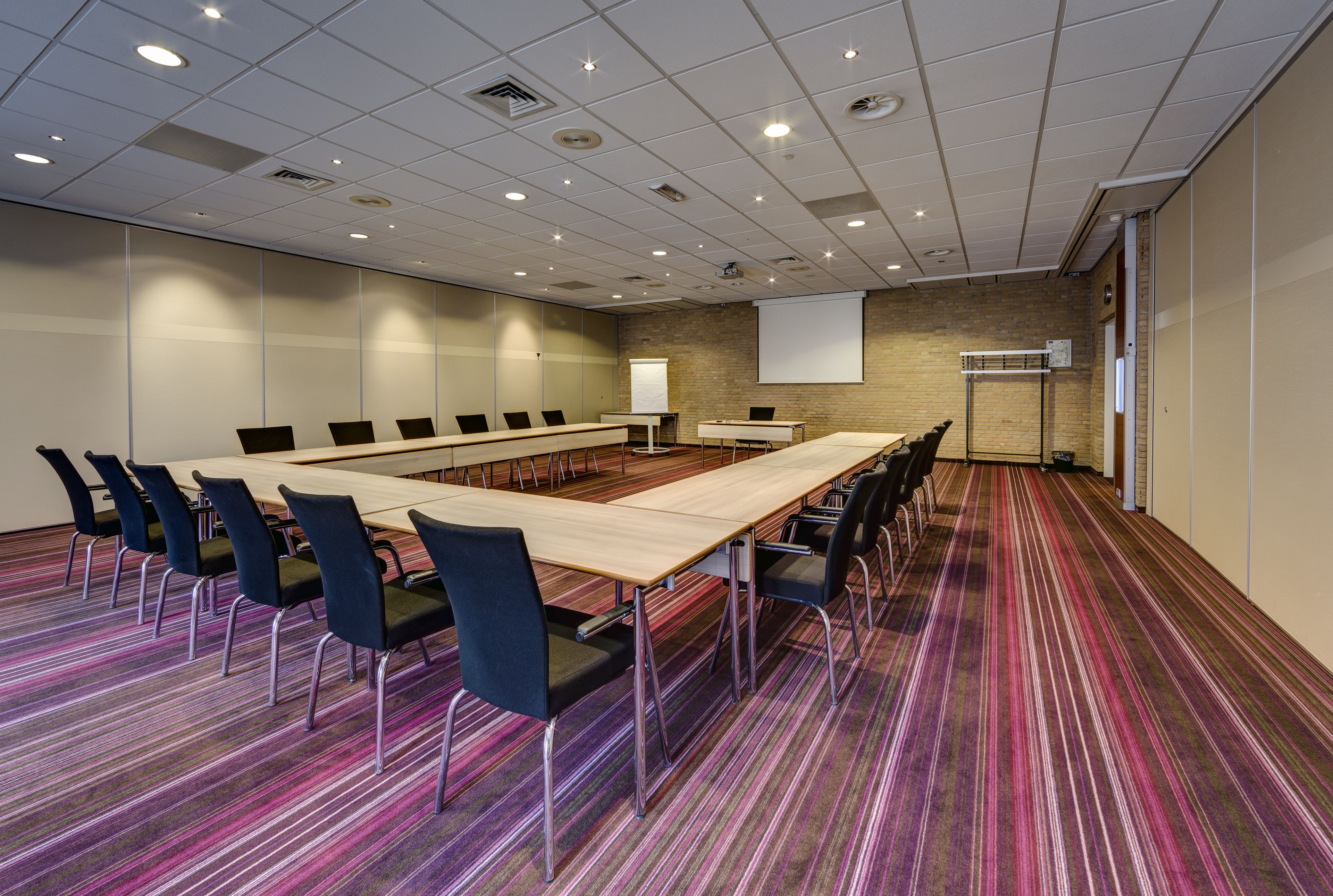 A conference room with a long table, chairs, a projector screen, and a whiteboard.