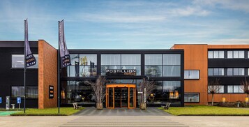 Un hotel moderno con fachada negra, ventanas amplias y una entrada acogedora.