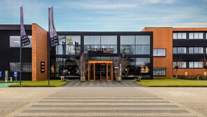 A modern hotel entrance with a glass facade, a prominent sign, and a paved driveway. - Postillion Hotel Deventer (Deventer)