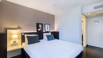 A hotel room with a large bed, a bedside table with a lamp, and two framed pictures on the wall.