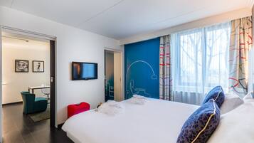 A modern hotel room with a large bed, a desk, and a television.