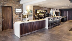 A reception area with a wooden reception desk, bar, and seating area. - Postillion Hotel Deventer (Deventer)